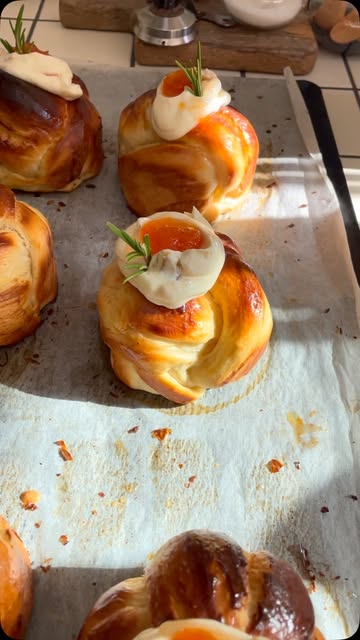 Des brioches torsadées dorées, garnies de crème et d’herbes, sur une plaque