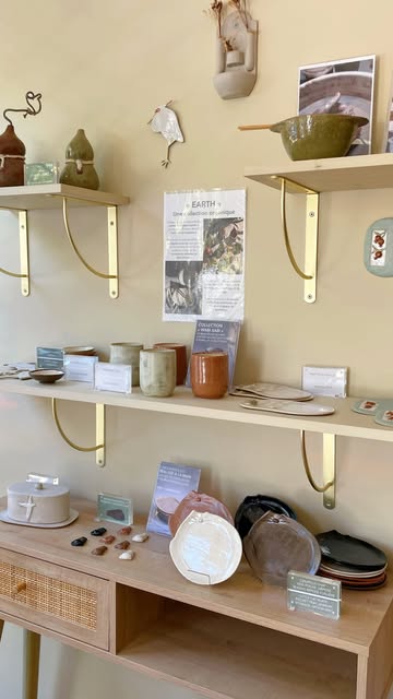Des étagères en bois et laiton garnies de céramiques et de petits objets